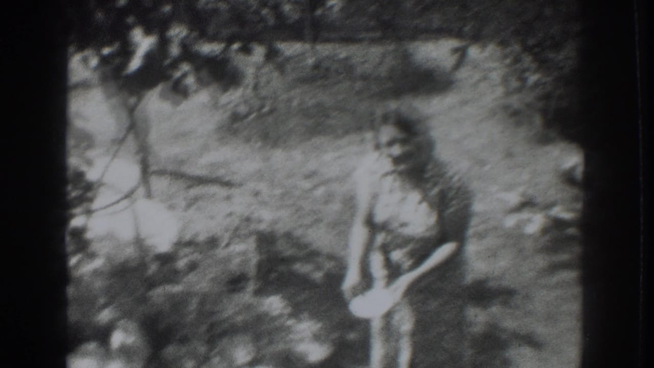 1937 Vacaville home-movie frame showing a woman in a patterned dress holding a light bowl among grass and trees.