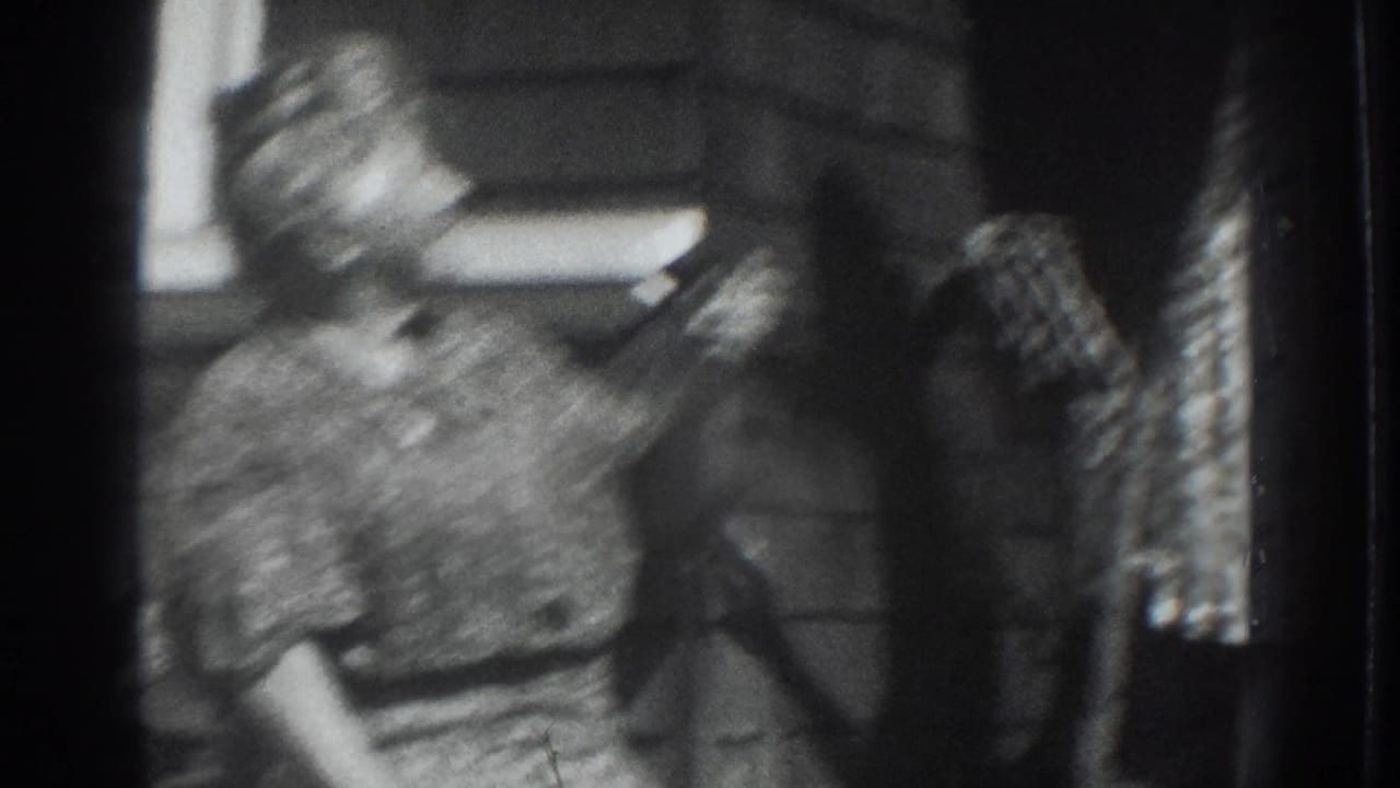 Blurred 1937 Vacaville home-movie frame showing a child or seated figure near a standing adult in a patterned dress.