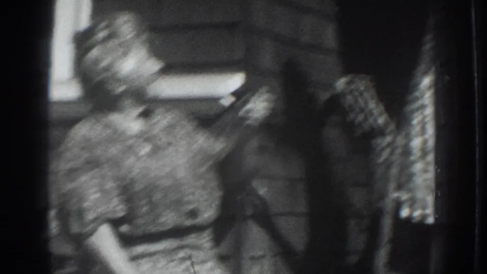 Blurred 1937 Vacaville home-movie frame showing a child or seated figure near a standing adult in a patterned dress.