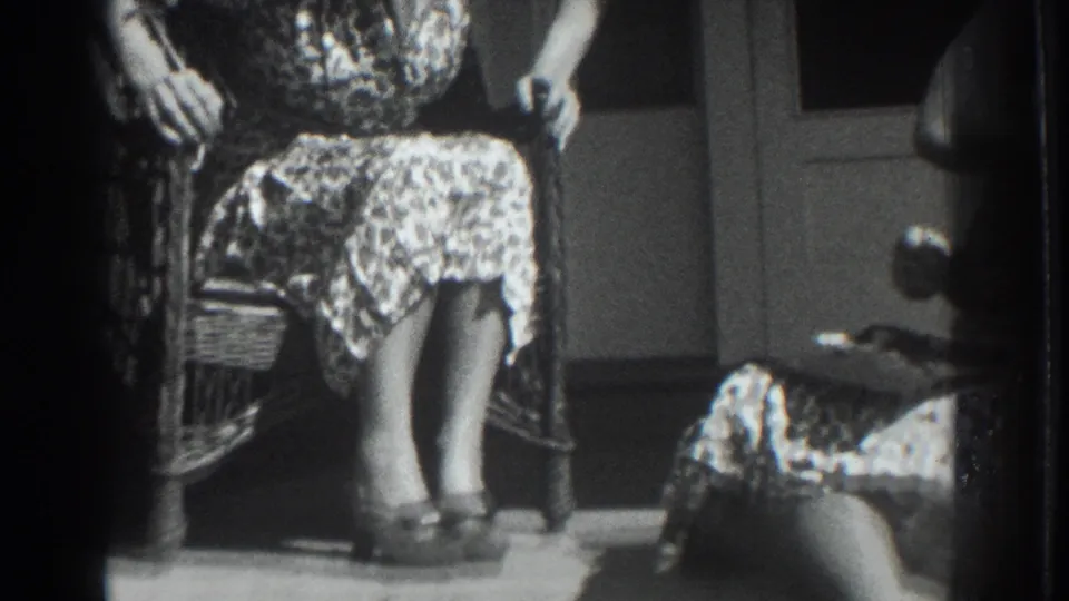 1937 Vacaville porch scene with three adult women in patterned dresses seated near wicker chairs and a doorway in bright sun.