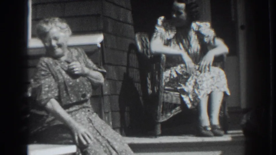 Two adult women in patterned dresses sit on a porch in Vacaville, California, in 1937 home-movie footage.