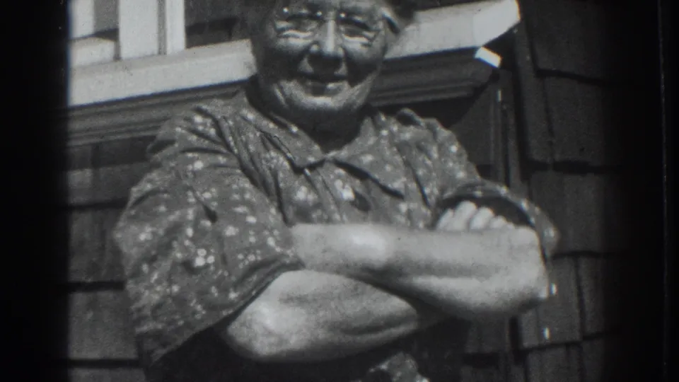 Final frame shows the older woman smiling with folded arms against a wood-sided house exterior in 1937 Vacaville footage.
