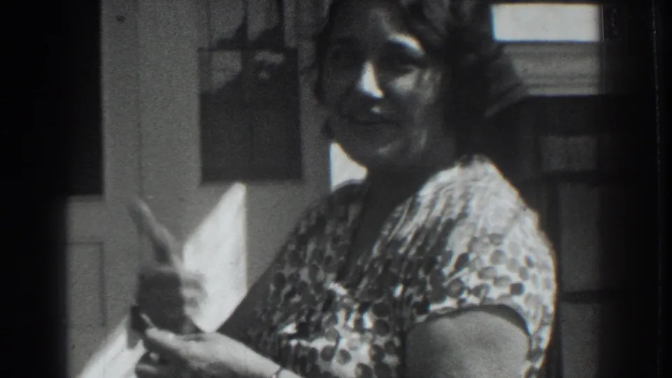 The woman smiles toward the camera near the white door, her patterned dress and hand-held object visible in the Vacaville footage.
