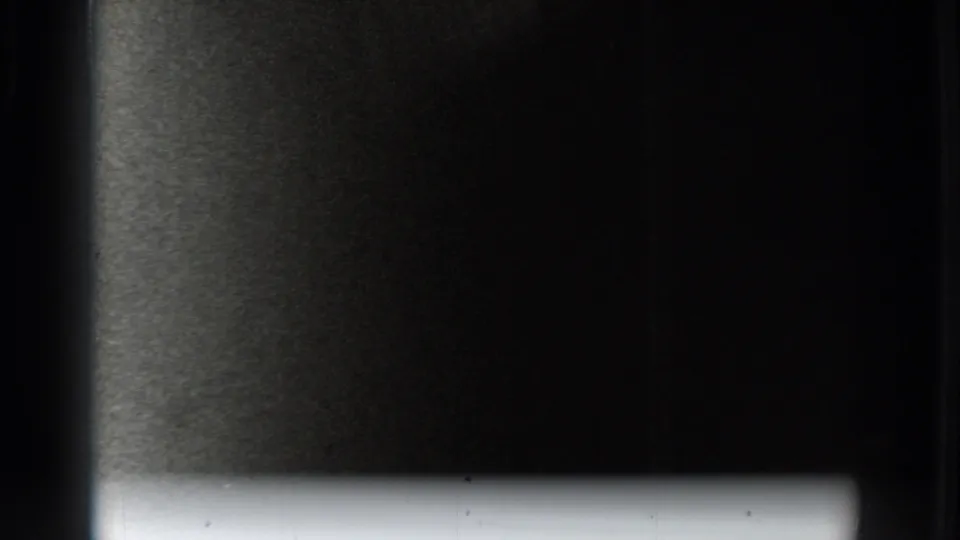 Dark 8mm frame from the 1937 Vacaville clip with a bright lower strip, heavy grain, and a partial exposure transition.