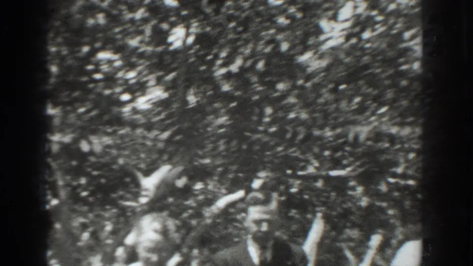 A family member appears among dense Vacaville orchard foliage, partly obscured by leaves in a grainy 1937 8mm frame.
