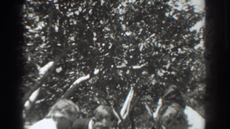 Final 1937 Vacaville frame shows several adults gathered under leafy orchard branches, partly cropped by the 8mm frame edge.