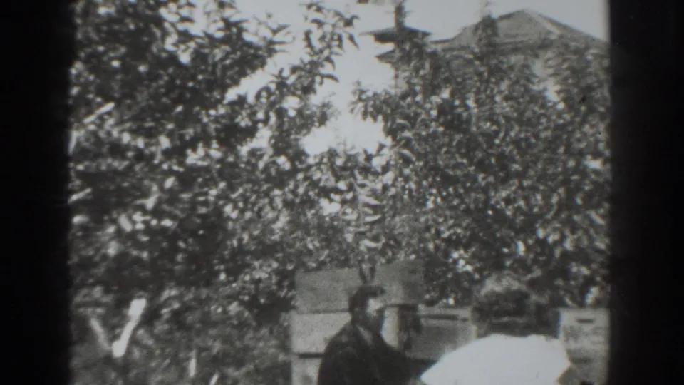 In 1937 Vacaville footage, a man and woman appear near stacked boxes beneath backyard trees.