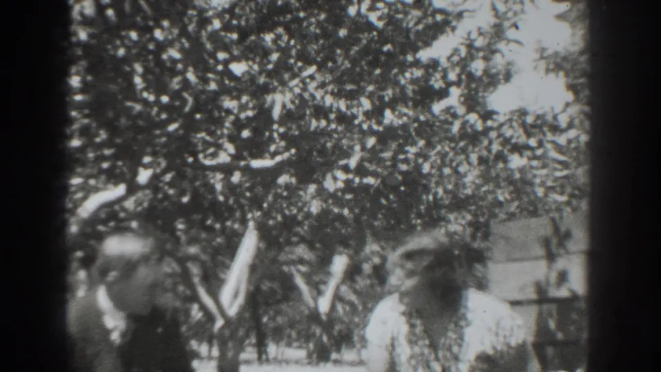 The man appears to eat fruit while the woman smiles or laughs in a shaded Vacaville garden scene.