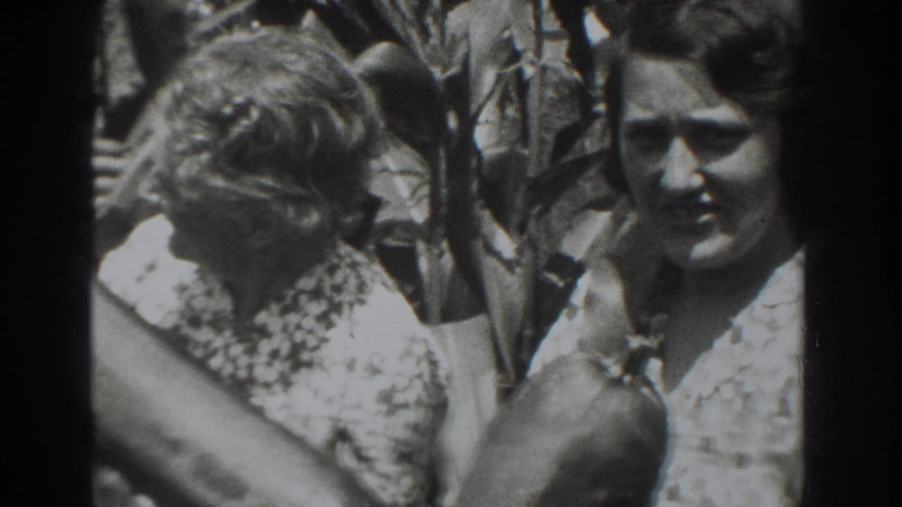 1937 Vacaville frame showing two women in patterned dresses beside leafy branches, with one facing the camera.