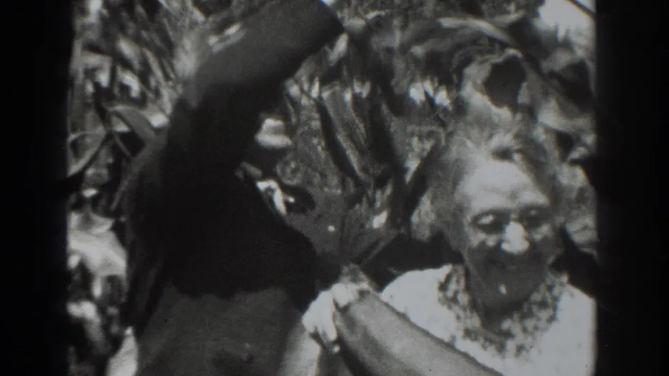In the 1937 Vacaville home-movie scene, an older woman and a man stand amid tall garden growth with oversized produce.