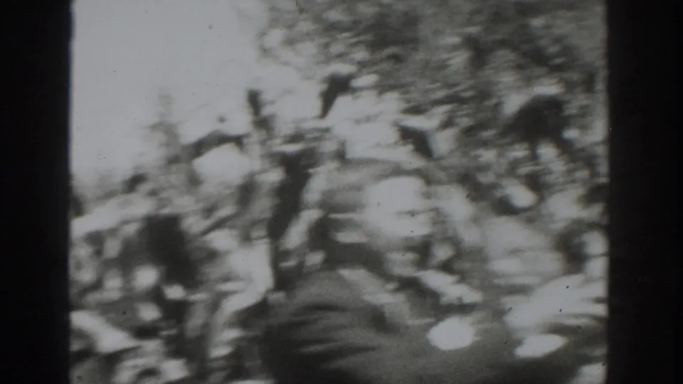 1937 Vacaville home-movie frame showing blurred adults among tall crop plants during an outdoor agricultural gathering.