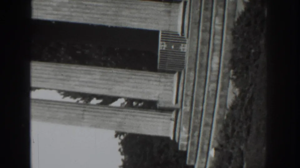 Upside-down Vacaville porch detail from the 1937 8mm clip, with awning, exterior wall, greenery, and visible film borders.