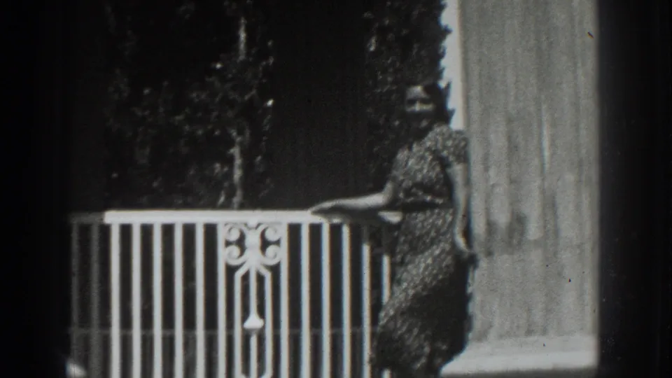 A slightly lower 1937 8mm frame shows the woman by the balcony railing, with the column and foliage still visible.