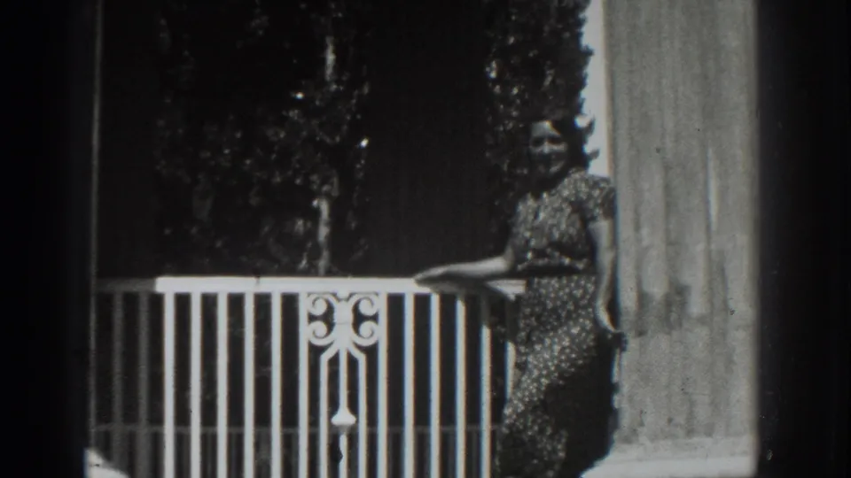 The clip ends with the woman facing the camera beside the white balcony railing and column in the Vacaville home movie.