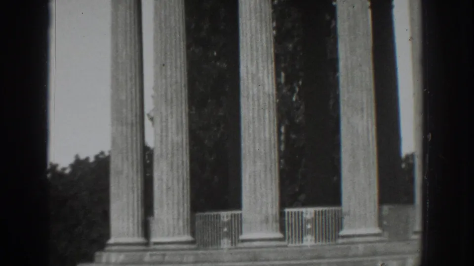 1937 Vacaville home-movie frame showing classical fluted columns, railings, tree silhouettes, and visible 8mm film borders.