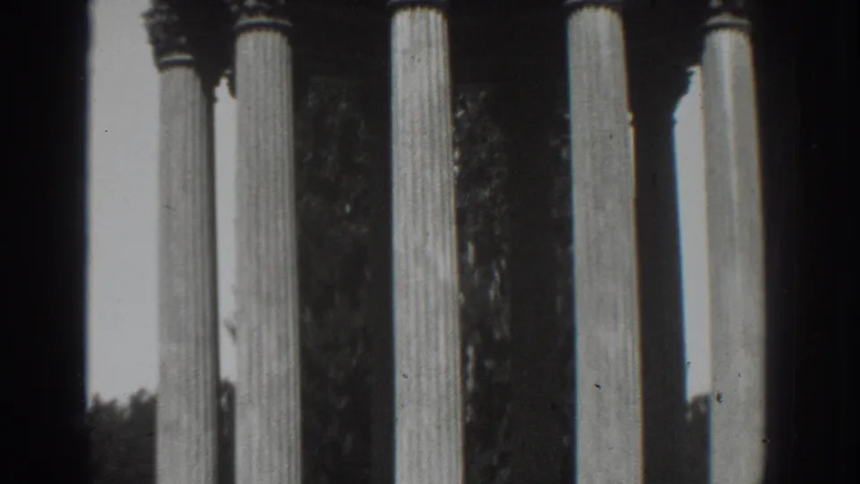 1937 Vacaville 8mm frame of a classical columned structure, dark trees, railings, and slight vignetted film edges.