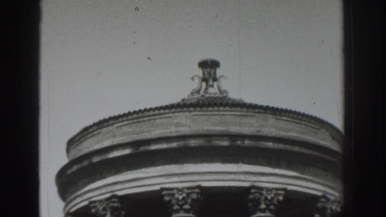 Upper portion of a circular classical building with columns and a domed roof edge.