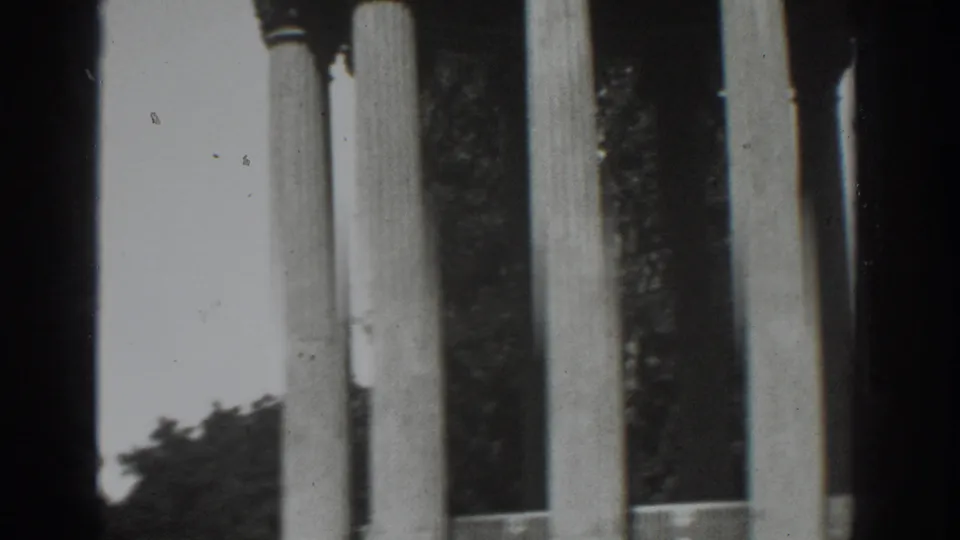 Black-and-white 8mm frame from Vacaville, 1937, showing tall columns against trees and bright sky.
