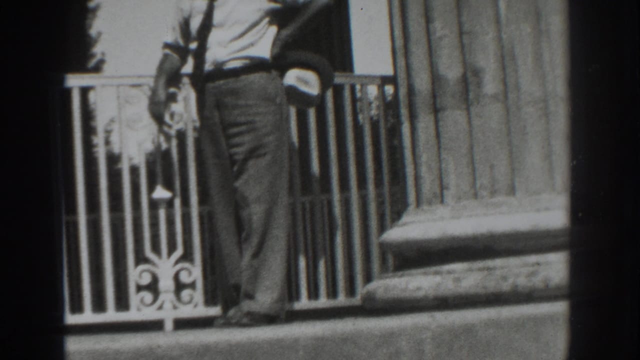 A man in 1937 Vacaville home-movie footage moves past an ornate white railing and heavy fluted column.