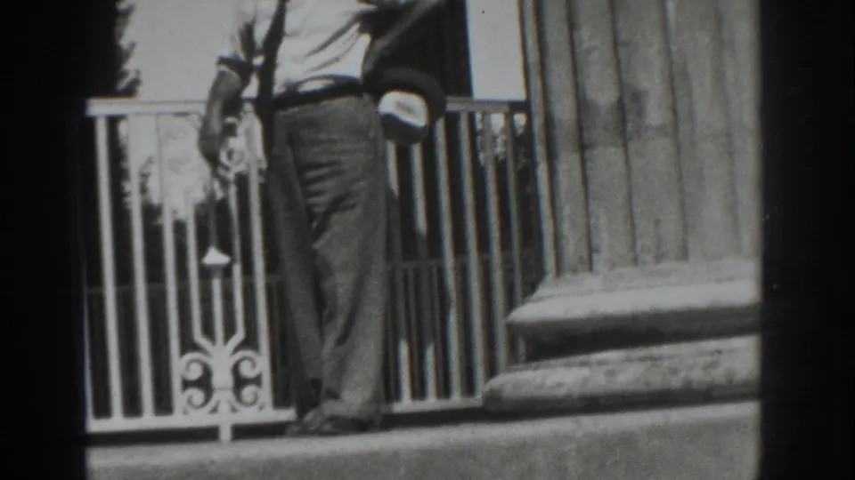 A man in 1937 Vacaville home-movie footage moves past an ornate white railing and heavy fluted column.