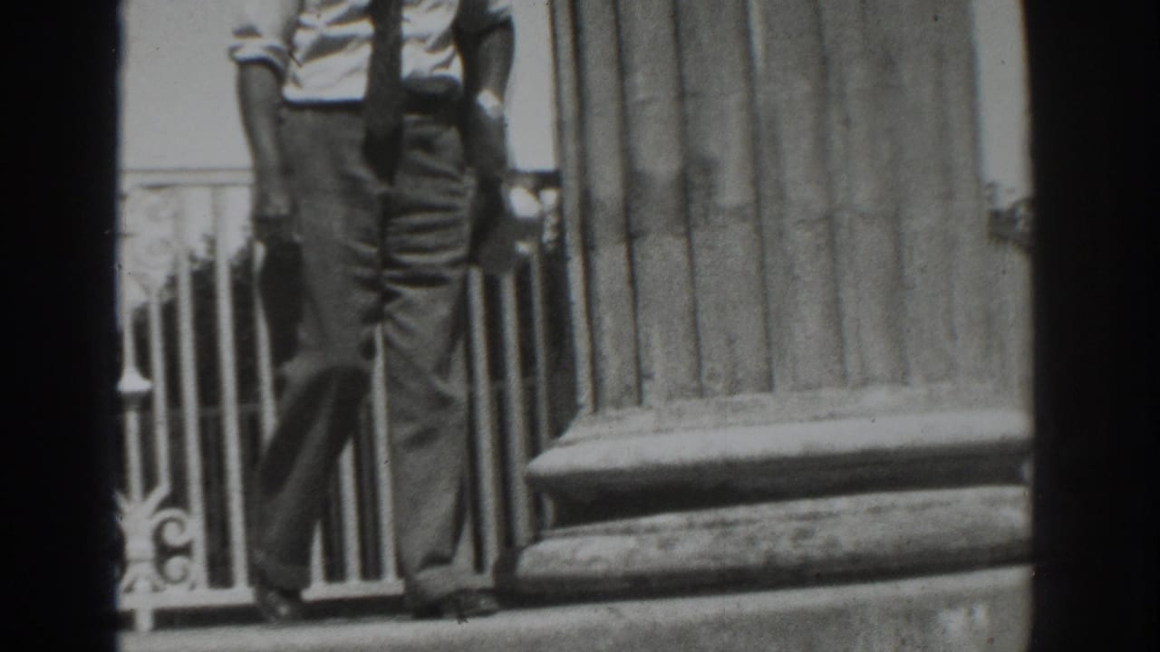 Near the end of the 1937 Vacaville clip, the man carries a light hat while walking past the column and railing.