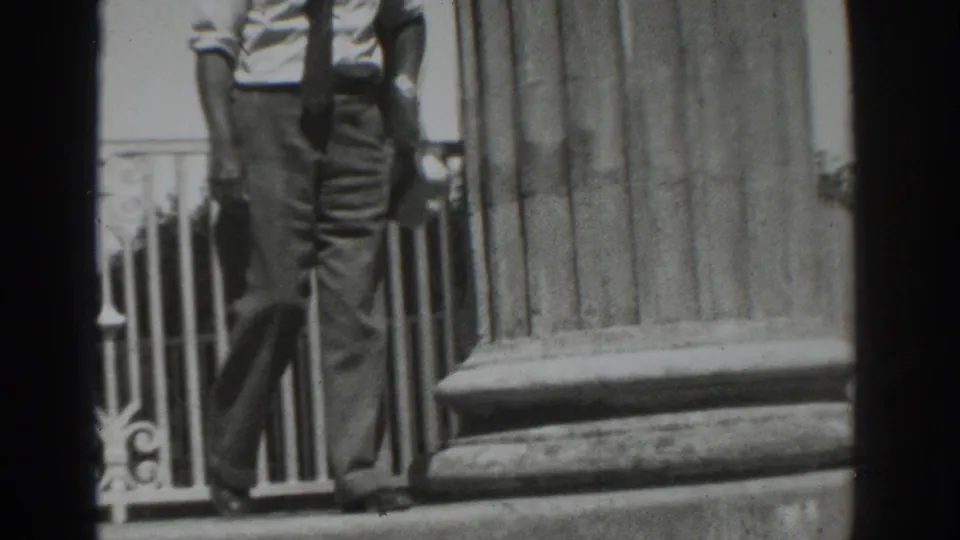 Near the end of the 1937 Vacaville clip, the man carries a light hat while walking past the column and railing.