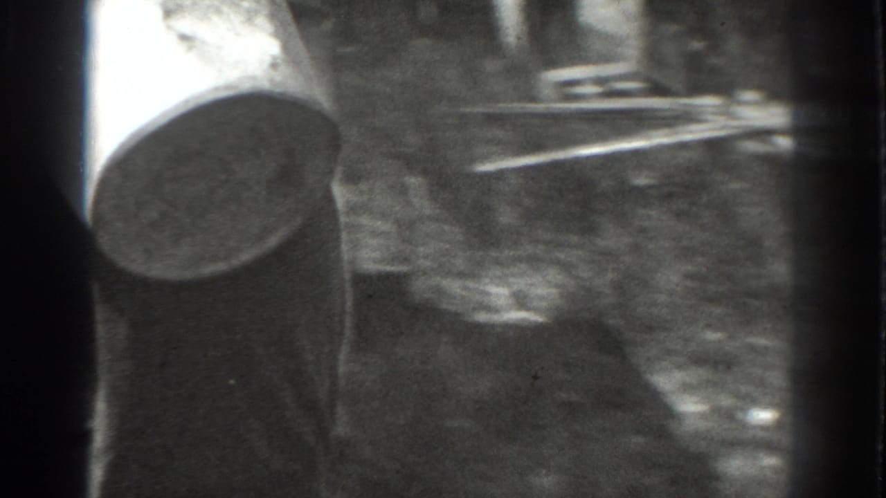 1937 Vacaville 8mm frame with a partial wide-brimmed hat, sunlit ground, and heavy film border at the edge of the shot.