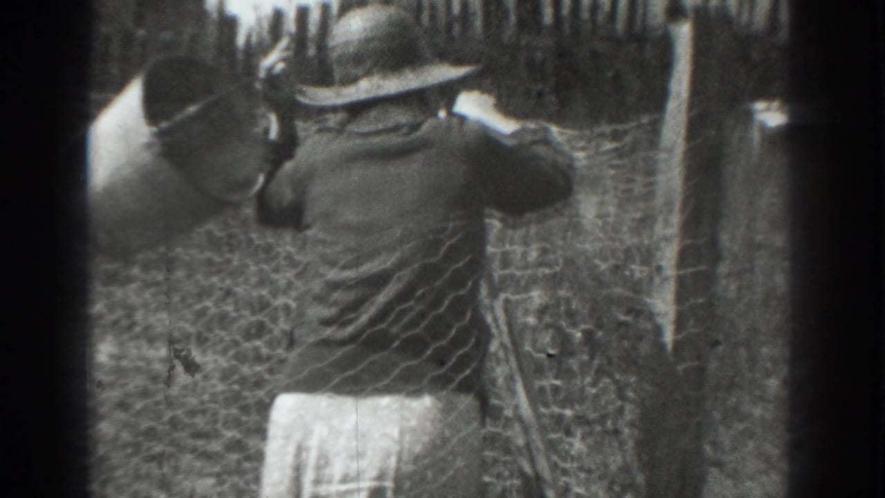 In 1937 Vacaville home-movie footage, a woman in a wide-brimmed hat works near chicken wire fencing and rough wooden posts.