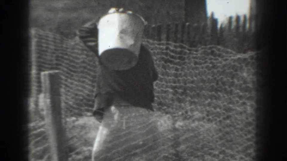 The woman continues downhill beside the fence, her bucket prominent against the rural Vacaville setting.