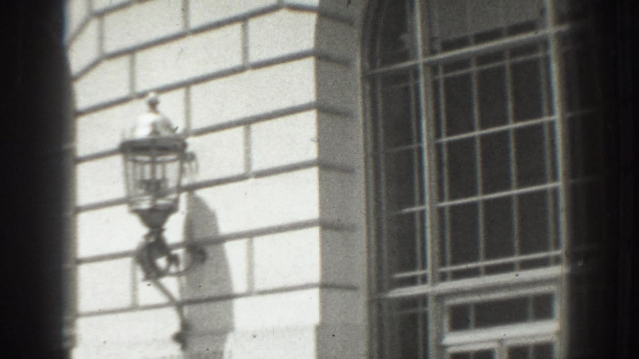 Stone building corner with barred windows and a lantern-style wall fixture.