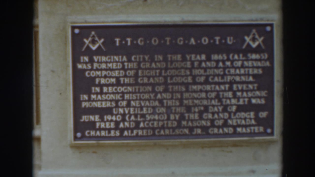 Bronze Masonic memorial plaque mounted on a stone wall.