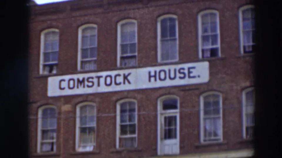 The Comstock House sign appears across the red brick building, with tall sash windows above and below in the 1937 Virginia City footage.