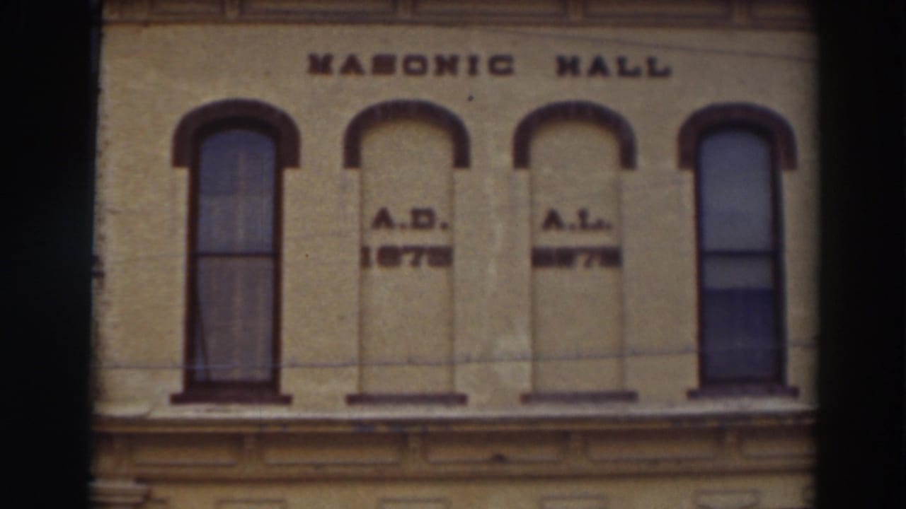 Upper facade of a Masonic Hall building with arched windows and painted lettering.