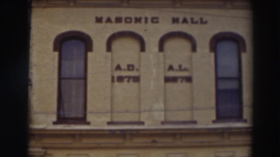 1937 8mm view of the Masonic Hall facade in Virginia City, California, showing arched windows and date lettering.