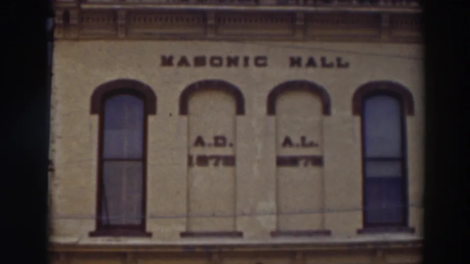 Upper story of the Virginia City Masonic Hall, with bold wall lettering, arched window openings, and reddish trim.