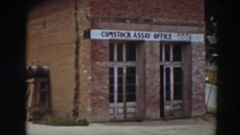 Final 1937 8mm view of the Comstock Assay Office in Virginia City, California, with sign, brickwork, and doors held in frame.
