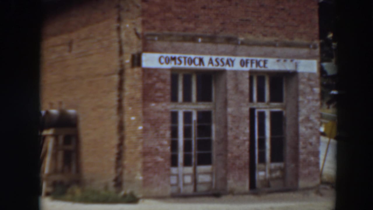 Brick Comstock Assay Office facade with sign, doors, and tall windows.