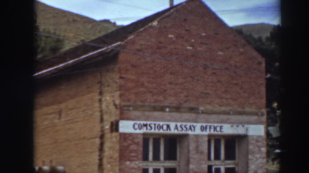 Brick Comstock Assay Office building with sign, gabled roof, windows, and hillside behind.