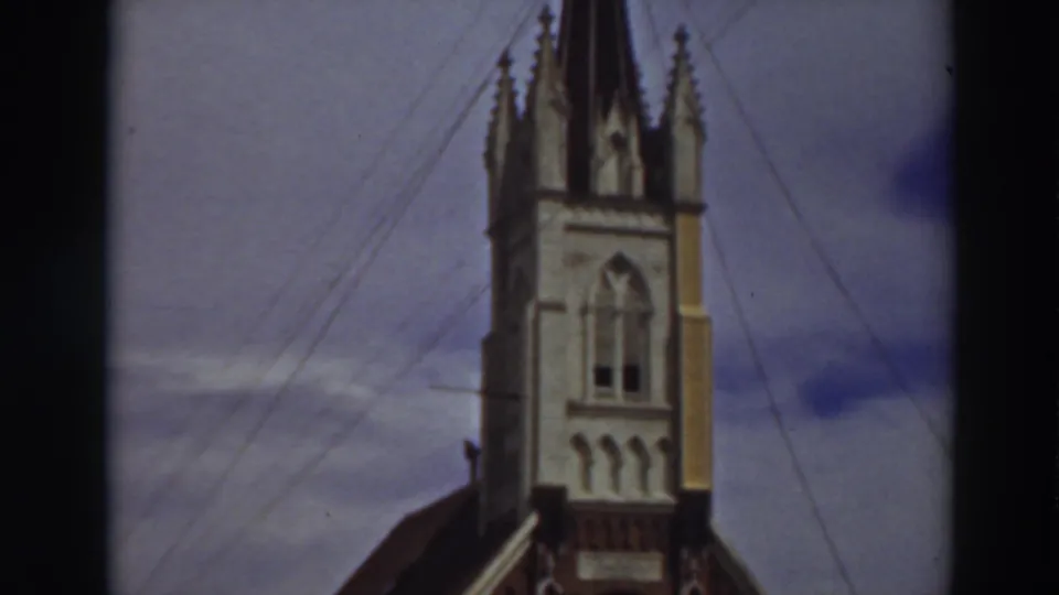 1937 Virginia City, California 8mm frame centered on a Gothic-style church steeple with arched window, spires, and crossing wires.