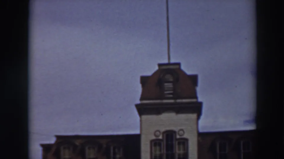 The camera holds on the Historic Bowers Mansion tower and dormered roofline, with soft focus and dark 8mm frame edges.