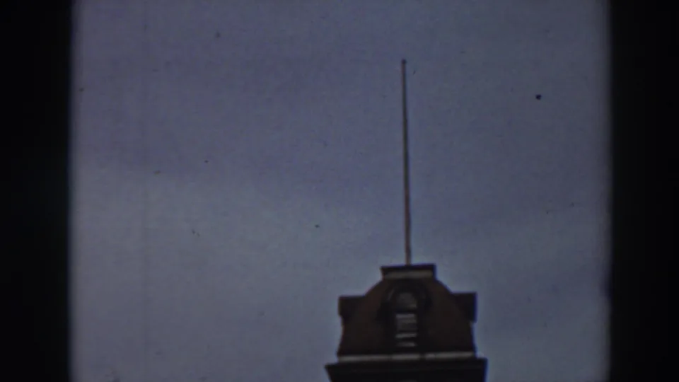 The upward framing leaves the mansion tower near the bottom of the 1937 8mm frame, with a long flagpole extending into the sky.