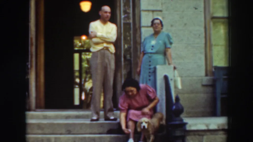 At Historic Bowers Mansion, two adults stand on the steps as a seated girl or young woman in pink leans toward a small dog.