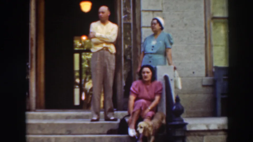 Home-movie frame of a family on porch steps in the supplied Virginia City, California clip, with a dog beside the seated woman.