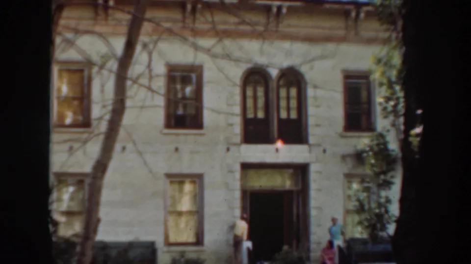 Final wide frame showing the large building exterior, three adults, and a small dog near the Virginia City, California entrance.