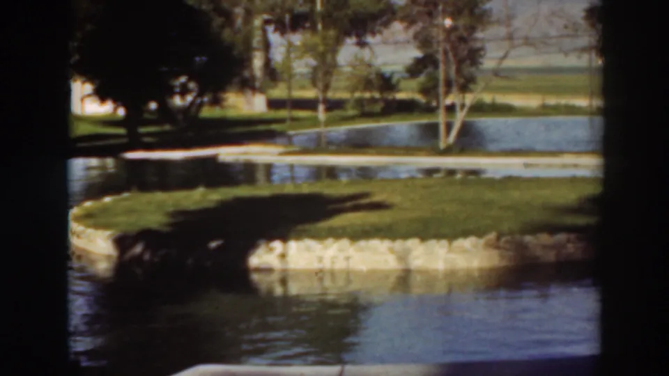 Final sampled frame shows the pond, grass island, stone edging, and shaded trees in the reported 1937 Virginia City California home movie.