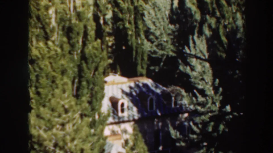 Final frame holds on the distant house and surrounding evergreens in bright Virginia City sunlight.