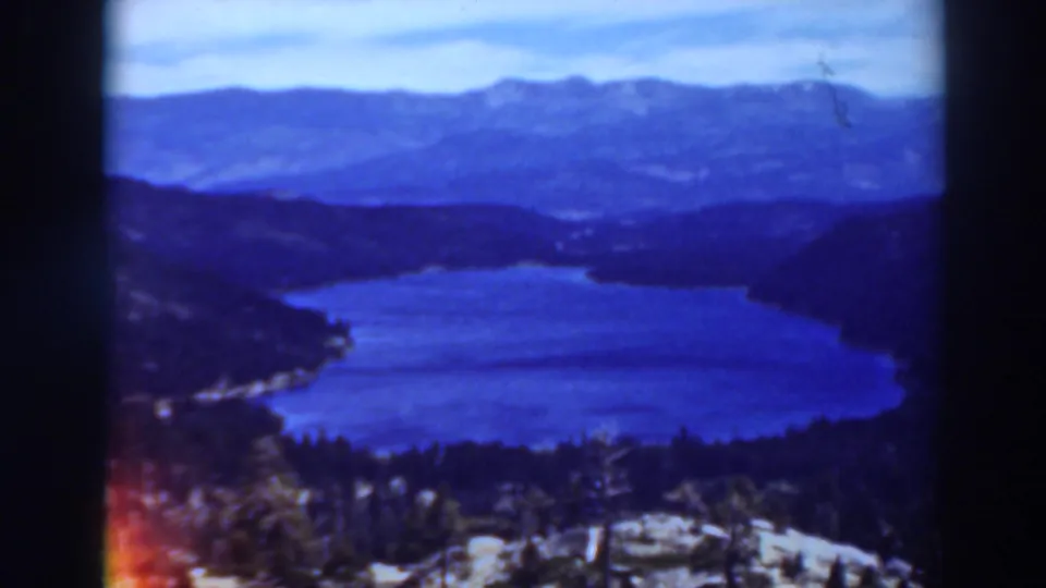 1937 8mm landscape frame of the stated Virginia City, California area, with a blue lake below layered forested mountains.