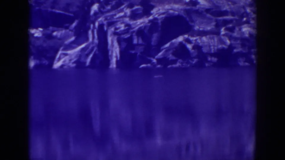 Angora Lakes shoreline rocks reflected in still water, seen in soft 1938 8mm color footage.