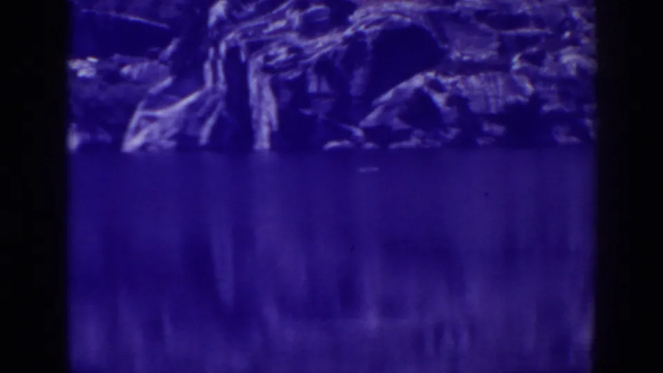 1938 Angora Lakes scenic frame with dark film edges, shoreline rocks, and calm reflected water.
