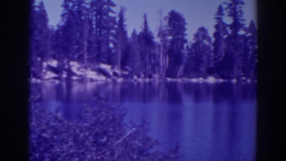Angora Lakes, California, appears in a purple-blue 8mm frame with forested shoreline and calm reflective water.